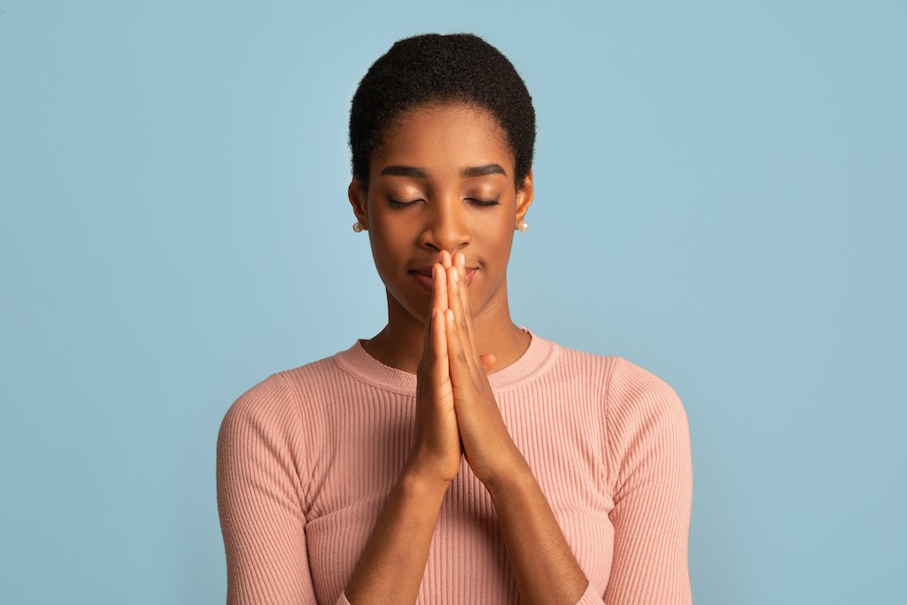 black woman with hands clasp in front of face