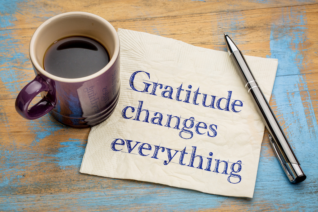 "gratitude changes everything" printed on a napkin next to cup of coffee